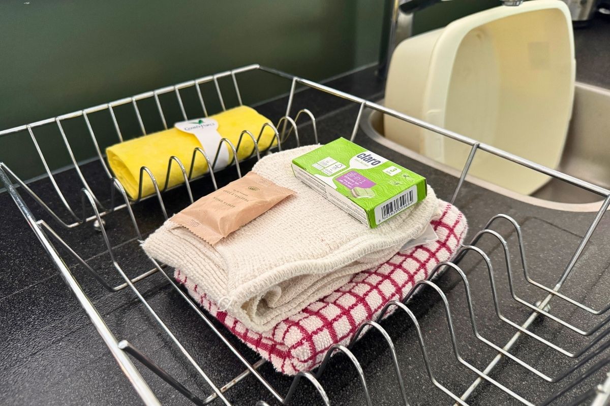 Starter pack washing supplies unpacked in a Woodland Lodge kitchen at Center Parcs Whinfell Forest, showing the dishcloth bundle that contains the washing-up sachet and spare bin liner