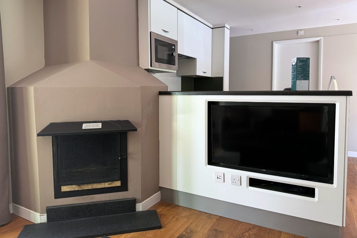 TV built into the kitchen divider and log burner in the living space of a two-bedroom Woodland Lodge at Center Parcs Whinfell Forest