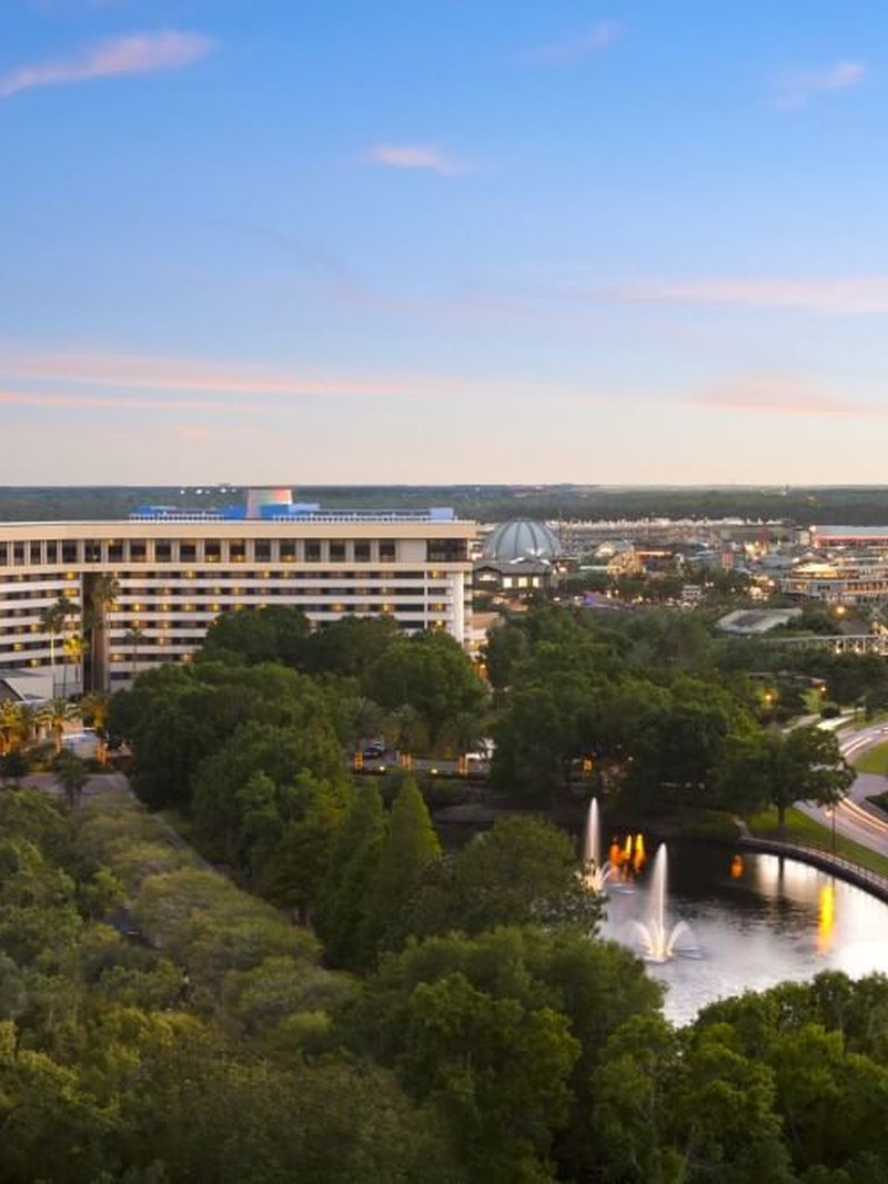 Hilton Orlando Lake Buena Vista exterior at dusk with Disney Springs in the distance